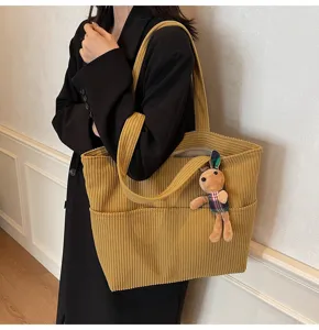 Detailed shot of the yellow corduroy tote bag featuring large capacity and a cute rabbit pendant.
