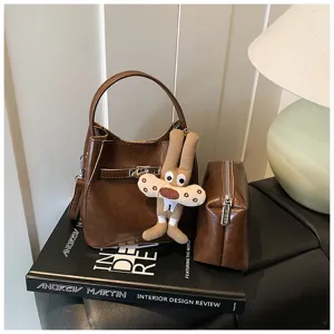Elegante borsa a secchiello in pelle marrone con ciondolo coniglio, borsa chic da donna per lavoro.