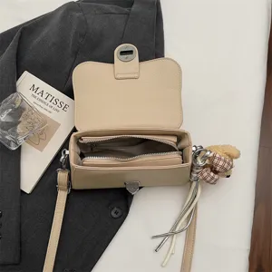 Borsa a tracolla in pelle beige vista principale, borsa quadrata con serratura metallica e peluche.