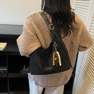 Women casual black shoulder bag underarm hobo bag with beaded pendant for autumn daily commute.
