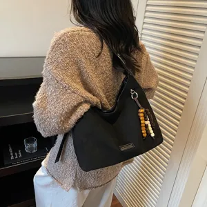 Stylish black suede shoulder hobo bag for women with beaded charm, casual daily wear.