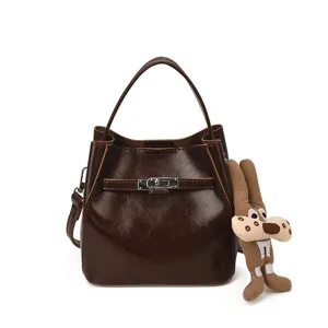 Borsa a secchiello in pelle marrone scuro con manico e ciondolo di peluche per donna.