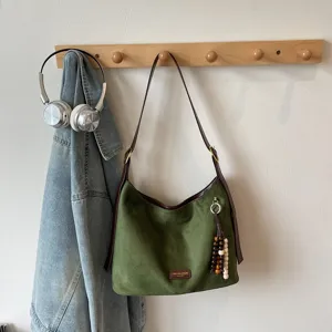 Retro green suede shoulder bag detail view with brown leather strap and wood bead pendant.