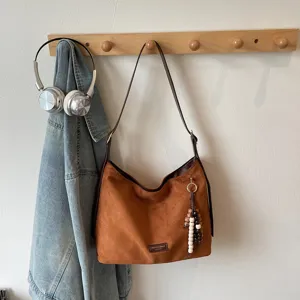 Retro brown suede shoulder bag for women, casual commuter hobo tote with chic beaded charm.