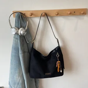 Retro black suede shoulder bag for women, casual underarm tote with chic beaded pendant charm.