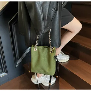 Close-up detail of the olive green suede bucket bag featuring chain strap and drawstring.
