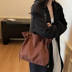 Retro brown suede chain tote bag for women, stylish slouchy shoulder bag with drawstring detail.