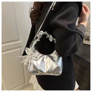 Vue rapprochée d'un sac argenté métallique avec poignée froncée et nœud en perles dentelle.