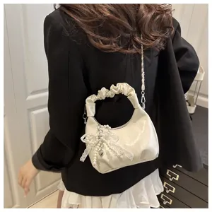 Gros plan sur le sac hobo plissé chic doté d'un délicat pendentif en dentelle de perles et chaîne.