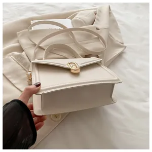 Détail de sac à main structuré de couleur crème, design minimaliste avec élégant fermoir doré.