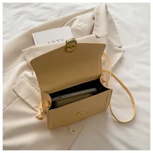 Vue détaillée du petit sac bandoulière jaune montrant l'intérieur ouvert et les ferrures.