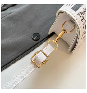 Vue détaillée d'un sac bandoulière blanc élégant avec imprimé journal et détails dorés.