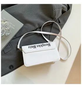 Vue détaillée du sac bandoulière blanc minimaliste avec lettrage noir et chaîne chic.
