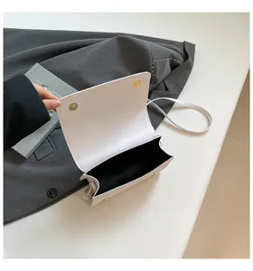 Vue détaillée du petit sac bandoulière blanc minimaliste avec rabat et quincaillerie dorée.