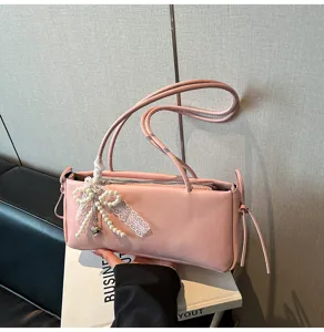 Close-up of pink shoulder bag featuring elegant pearl lace bow and delicate side strap details.