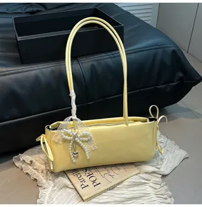 Stylish yellow shoulder bag with elegant pearl lace bow pendant, perfect for daily commute.