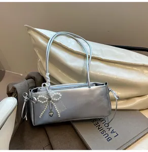 Silver metallic shoulder underarm bag with pearl bow pendant, stylish daily accessory.