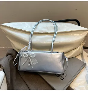 Detailed shot of silver shoulder bag with pearl bow accessory and elegant lace trim design.