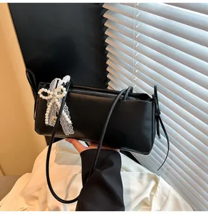 Detailed view of the black chic shoulder bag with pearl lace bow accent and sleek thin straps.