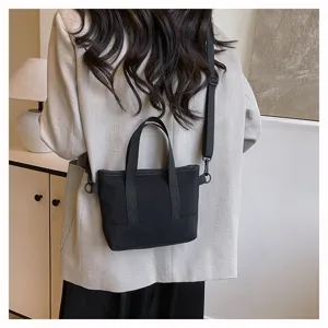 Minimalist black canvas crossbody bag detail, casual small shoulder tote with adjustable strap.