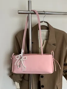 Pink PU leather shoulder bag for women, elegant underarm bag with pearl bow and long strap.