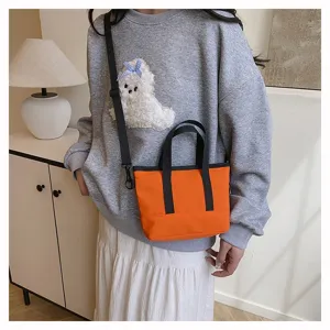 Orange canvas shoulder bag for women, casual crossbody small tote with black handles and strap.