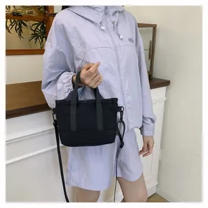 Detail view of black canvas crossbody shoulder bag, casual solid color design with dual handles.