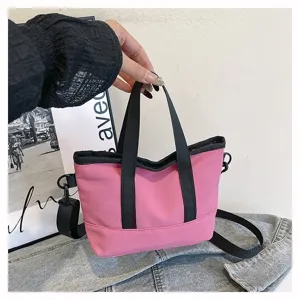 Casual pink canvas shoulder crossbody bag with black handles, compact daily handbag detail view.
