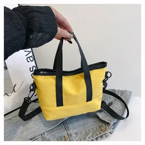 Detail shot of a trendy yellow canvas crossbody bag with black handles for daily casual use.