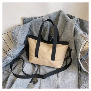 Detail view of casual solid color canvas cross-body shoulder bag with black handles.