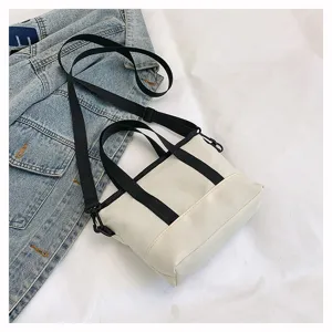 Detail shot of the casual white mini canvas crossbody bag with black straps in daily scene.