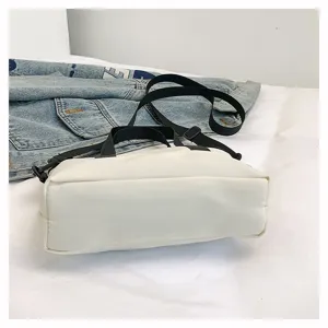 Casual solid color canvas crossbody bag detail shot, simple everyday shoulder bag with straps.