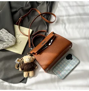 Bolso de mano Kelly retro de cuero marrón con correa y colgante de oso para mujeres.