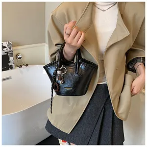 Nahaufnahme einer eleganten, glänzenden schwarzen Lackhandtasche mit tollem Anhänger.