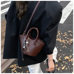 Detailansicht einer vintage dunkelbraunen lederhandtasche mit anhänger und griff.