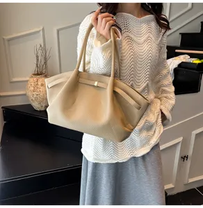 Vista dettagliata di una borsa tote beige chic con pieghe laterali e chiusura dorata da lavoro.