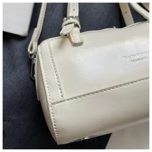 Detailed view of cream white oil-wax leather pillow bag, highlighting exquisite stitching texture.
