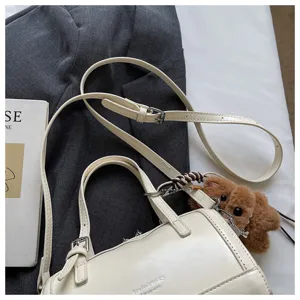 Cream white oil wax leather pillow bag, mini shoulder crossbody handbag with plush charm.