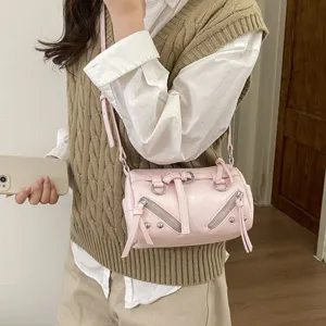 Pink cylindrical shoulder bag with metal zippers, studs, and tassels for daily commuting.