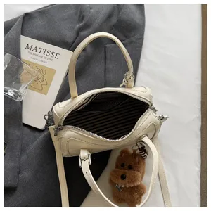 Detail shot of retro style oil wax leather handbag with striped interior and plush dog pendant.