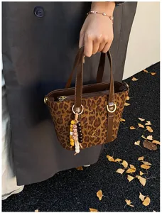 Detailed view of vintage leopard print suede bucket bag handle and beaded tassel charm.