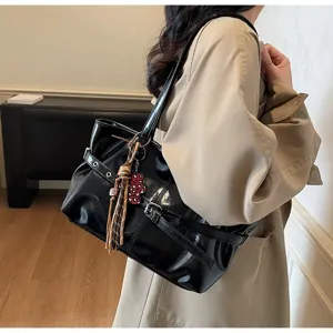 Borsa a tracolla nera in pelle verniciata con nappa e pendente per il commuting giornaliero.