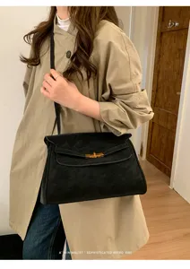 Schicke minimalistische schwarze Wildleder-Umhängetasche mit goldenem Drehverschluss.