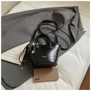 Schwarze glänzende Eimer Tasche für Damen, Retro Umhängetasche mit schicken Anhängern.