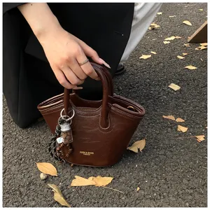 Detailaufnahme der braunen Vintage Lederhandtasche mit feinem Anhänger und Doppelgriffen.