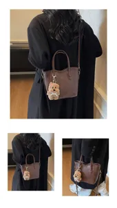 Detailed view of retro brown bucket handbag featuring cute plush bear charm and shoulder strap.