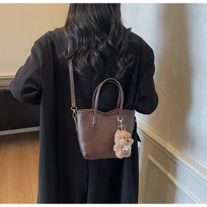 Vintage brown PU leather bucket bag for women, chic crossbody shoulder tote with cute bear pendant.