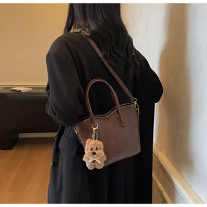 Detail view of the elegant vintage brown bucket bag featuring a cute plush bear keychain.