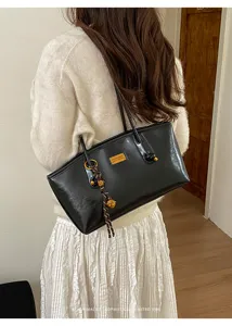 Vista detallada de un elegante bolso de hombro de cuero negro con estilo retro.