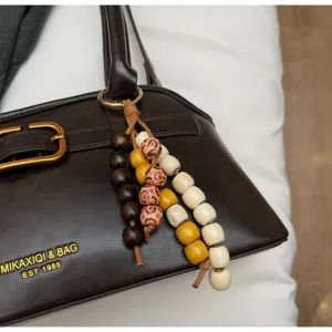 Brown PU leather underarm bag detail featuring vintage wooden bead charms and metal buckle accent.